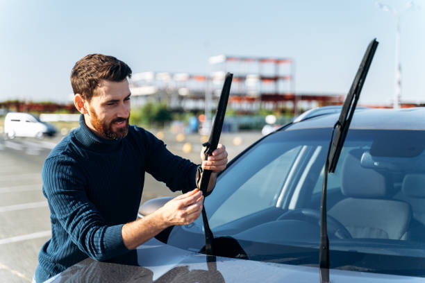 Male auto owner checking windshield wiper at the street Close up view of the man is changing windscreen wipers on a car. Male auto owner checking windshield wiper at the street. Automobile repair concept windshield wiper stock pictures, royalty-free photos & images