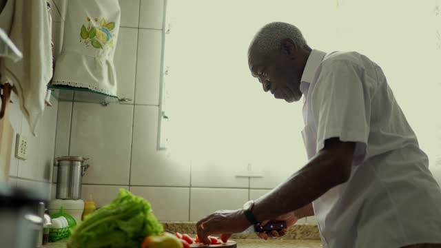 Senior man cutting tomatoes in the kitchen