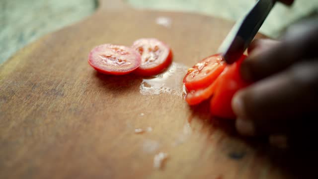 Close-up of a senior man cutting tomatoes in the kitchen