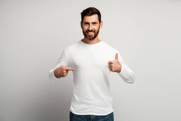 istock Optimistic handsome brunette man with beard in white shirt showing thumbs up 1472353702