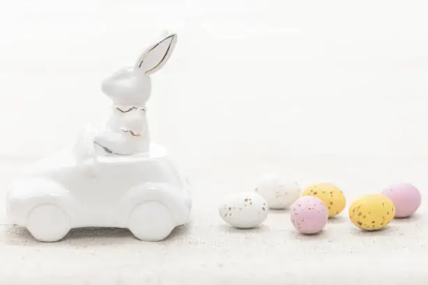Photo of Decorative ceramic hare in a car and Easter eggs, close-up.