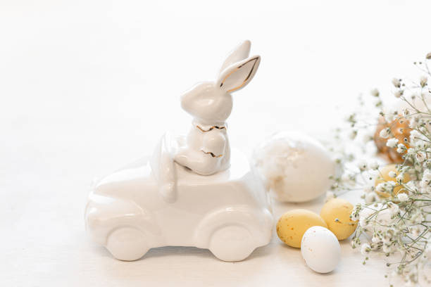 istock Easter background with a ceramic hare in the car and eggs on a white background, 1472354538