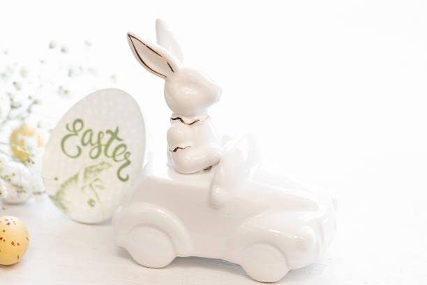 istock Easter background with a ceramic hare in the car and eggs on a white background, 1472354555