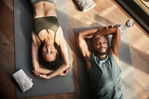 Black couple, yoga and relax on mat above for zen, spiritual wellness or peaceful exercise together. Man and woman yogi in fitness meditation relaxing or lying on floor in corpse or shavasana pose