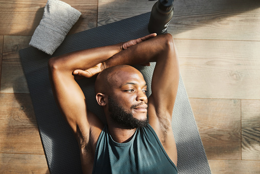 Top view, fitness and black man tired, thinking and sunshine with morning routine, training and exercise.  African American male, athlete and guy on floor, resting and relax with ideas and wondering