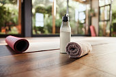 Water, towel and yoga mat in an empty fitness studio for wellness, mental health or inner peace closeup. Fitness, exercise and pilates with still life equipment on the floor of a gym for a workout