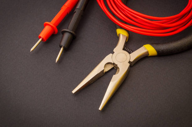 istock Electrician's tools and red wire on black background for repairing energized systems or communications 1472360713