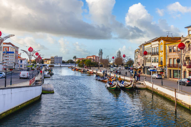 Gondeln fahren unter den mit Freundschaftsbänder verzierten Brücken über den Kanal do Cojo in ⁨‎⁨Aveiro⁩, ⁨Beira Litoral⁩, ⁨Portugal⁩.