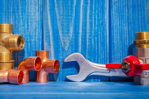 Spare parts with copper and plastic accessories for plumbing repair on blue vintage wooden boards