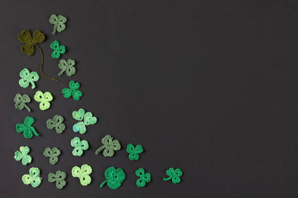 St Patrick's Day side border made of knitted green shamrocks on a black background. Holiday sign and knitted clover leaf. Copy space, flat lay, place for text