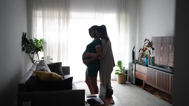 Pregnant lesbian couple dancing at home