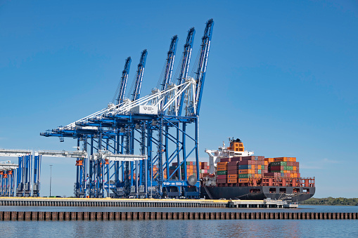 Charleston, SC, USA - March 09, 2023, 2023: Gantry cranes and ship-to-shore cranes ready to load and off-load container vessel Hudson Express at Leatherman Terminal in Charleston Harbor.