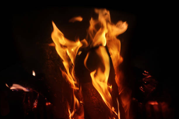 bright orange flame, blurred firewood burns in stove, fireplace in dark, burning stone and enjoying warmth, cozy winter evening at home concept, relaxing by home fire, energy problem of population llama naranja brillante, leña borrosa quemaduras en la estufa, chimenea en la oscuridad, piedra ardiente y disfrutar del calor, acogedora noche de invierno en el concepto de casa, relajarse junto al fuego del hogar, problema energético de la población