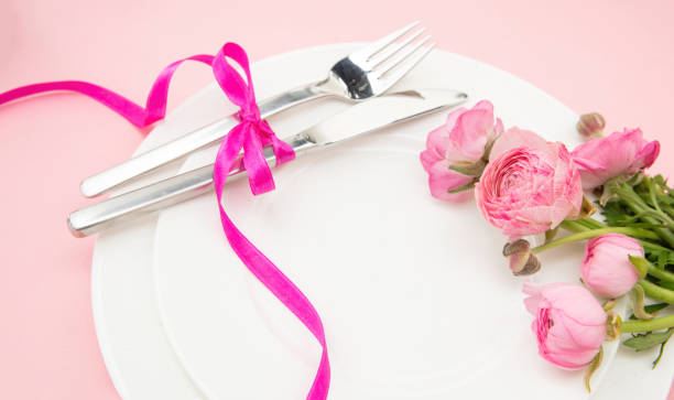 istock Spring Holiday table setting, Pink buttercup flowers and cutlery on white plates, closeup 1472373093