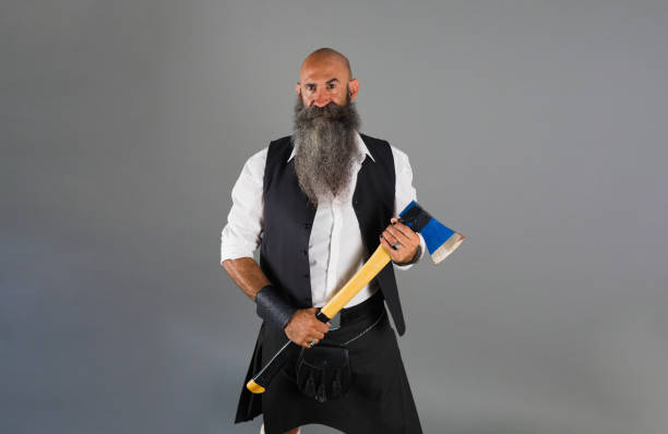 istock a shaved head man with a long beard standing ahead a gray background while holding an axe and look at camera 1472373212