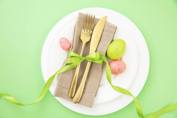 istock Easter table setting, Easter eggs decoration, napkin and golden cutlery on white plates 1472373228
