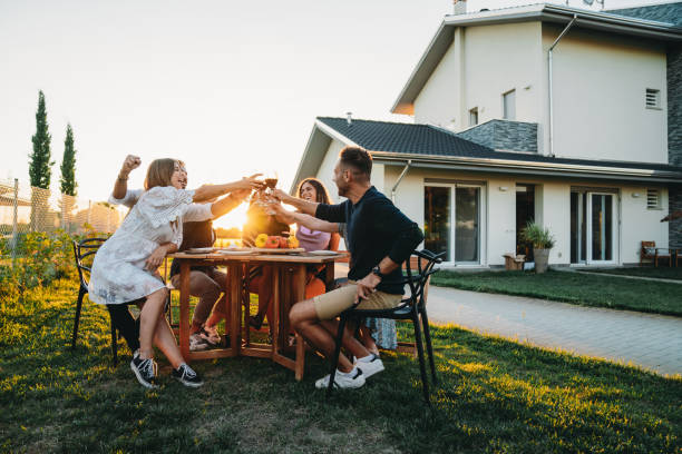 Friends are toasting together with red wine at sunset Friends are toasting together with red wine at sunset. Dinner party with friends in the backyard. big family sunset stock pictures, royalty-free photos & images