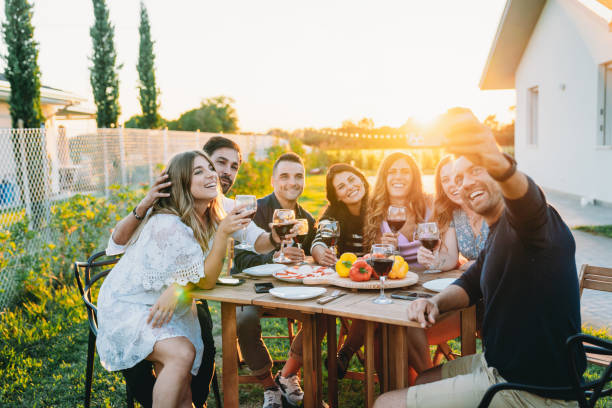 Friends are taking a selfie together during a dinner party Friends are taking a selfie together during a dinner party. Pov view of friends toasting together. big family sunset stock pictures, royalty-free photos & images