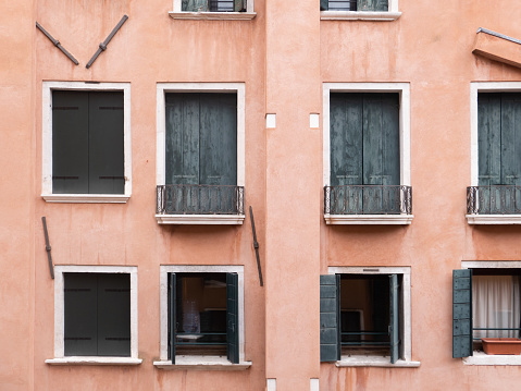 The exterior view of apartment building windows of an old weathered pink building.