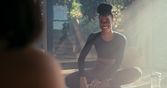 Friends, yoga or black woman talking to relax after group training or fun fitness workout together. Women, bonding or healthy people with a happy smile in conversation speaking of gossip in studio