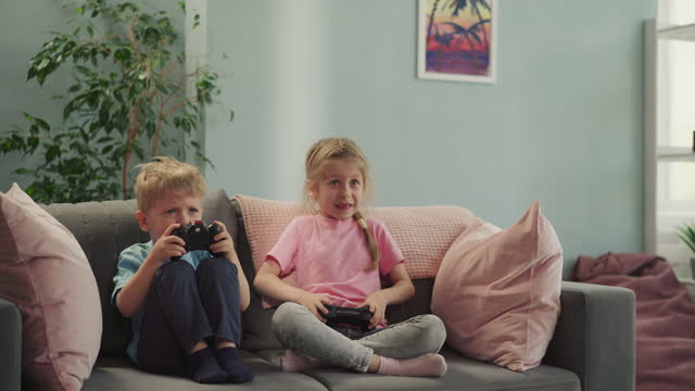 Happy siblings control gaming consoles to compete in game