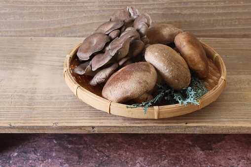 Maitake mushrooms and shiitake mushrooms on a bamboo colander.