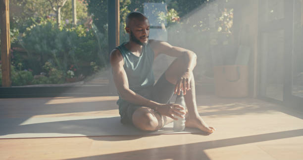 istock Relax, thinking or black man drinking water after yoga or pilates meditation training, workout exercise. Tired, fitness or zen person with a bottle for liquid hydration on resting break in studio 1472380333