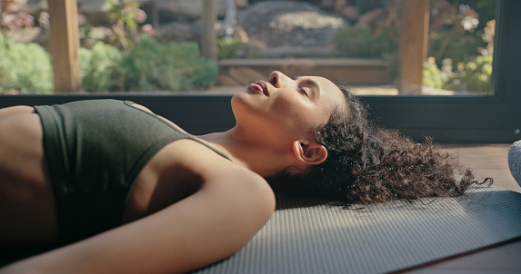 Meditation, yoga and zen of black woman on a pilates studio floor for fitness and wellness. Rest, relax and peace practice of a young person sleeping on the home gym ground for balance and chakra