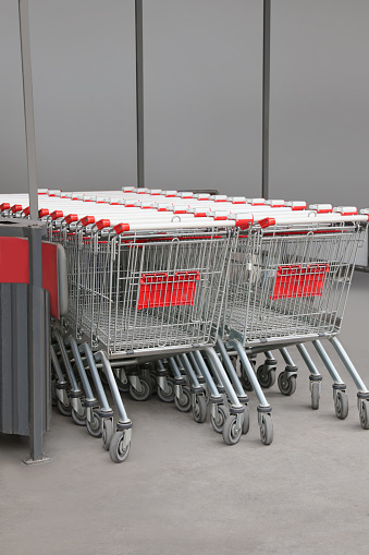 Many empty metal shopping carts near supermarket outdoors