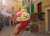 Woman hand hold   sweet ice - cream cone with different flavors  held in hand  in  Rovinj