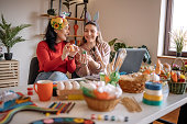 Two young women friends having fun at home with preparing Easter decoration