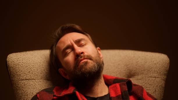 A studio portrait of a handsome man sitting on a sofa.