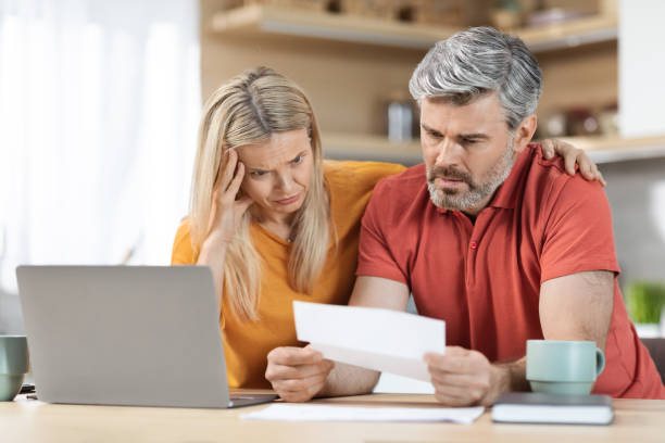 istock Anxious middle aged husband and wife checking correspondence, kitchen interior 1472383480