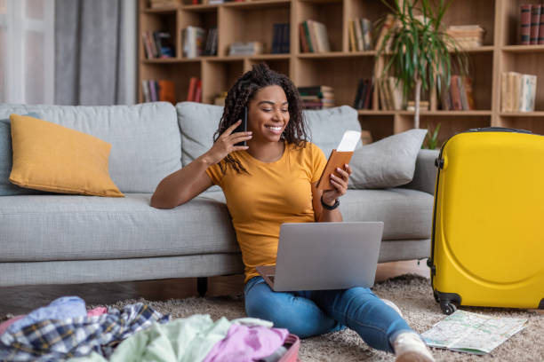 istock Excited african american lady using laptop and talking on phone while searching summer trip, preparing for holidays 1472384478