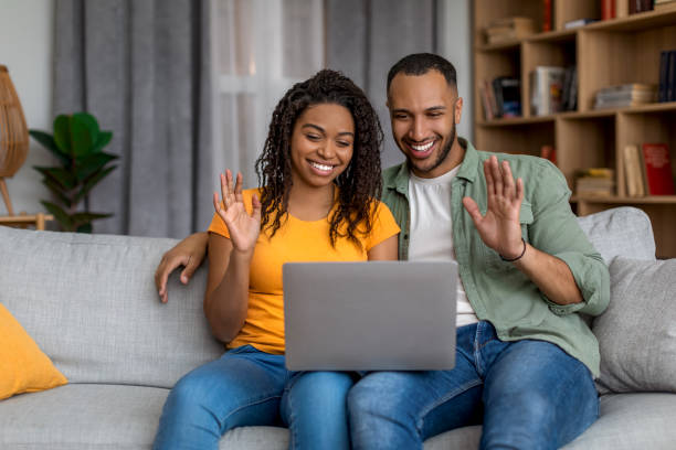 istock Modern remote communication. Happy black couple making video call from home using laptop and waving to webcam 1472384738