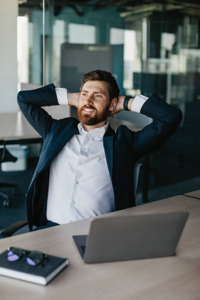 istock Taking break from work. Excited businessman relaxing on chair, leaning back at workplace and holding hands behind head 1472385089