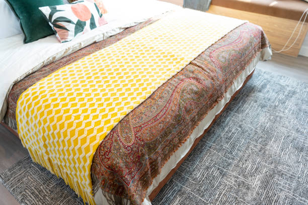 istock Bed with yellow throw blanket and grey rug in bedroom. 1472389786
