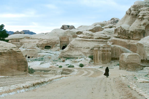 одинокая фигура, идущая к каньону аль-си�к рано утром, петра, иордания, ближний восток. - petra antiquities jordan middle east стоковые фото и изображения