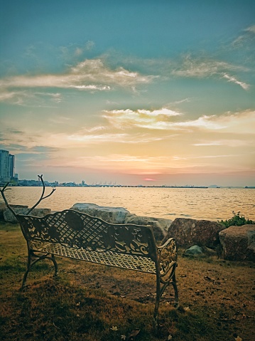 lounge chairs, sea, sky, sun, rocks, piers, clouds, picture of the evening sea where the sun is about to set There is a chair to sit comfortably on a lonely day. This picture conveys the atmosphere of loneliness. to sit and look into the distance relax photo shoot location by the sea Chonburi Province, Thailand