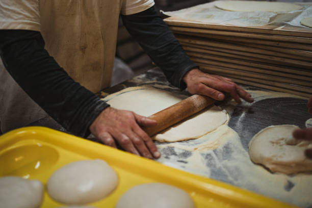 istock Baker flattening pizza dough with rolling pin 1472395717