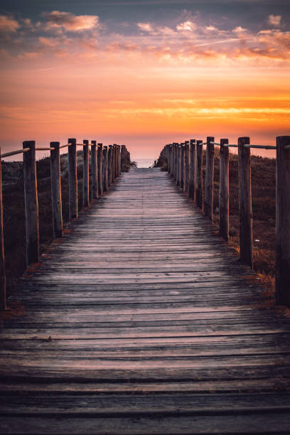 istock Strolling into the sunset: a boardwalk to the beach 1472395944