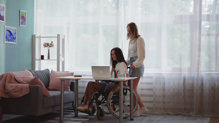 Woman pushes friend in wheelchair with muscular dystrophy