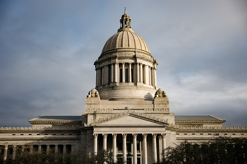 A dramatic view of the capitol building in Olympia, Washington, the morning sun casting dramatic shadows on the beautiful stone architecture.