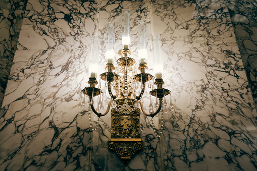 An intricate glass and crystal light fixture mounted on a marble wall in the state capitol of Washington state, USA.
