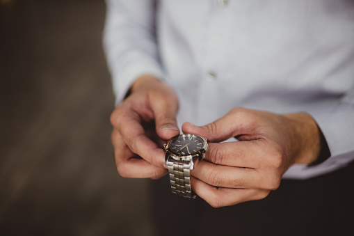 Man holding a silver wrist watch in his hands