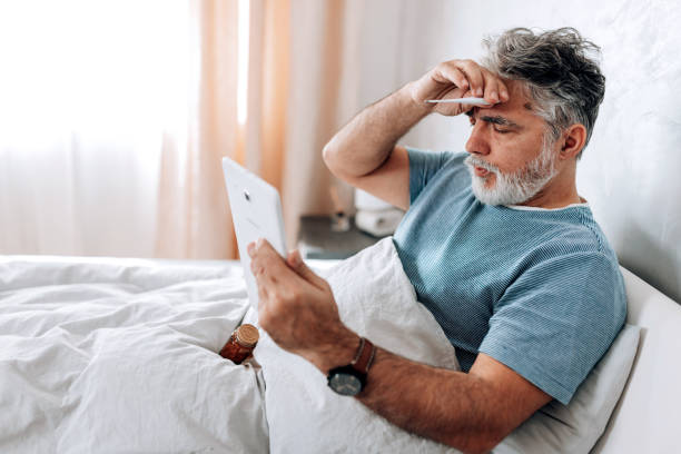 istock Mature Man Checks His Temperature During Virtual Doctor Visit from Bed 1472399543