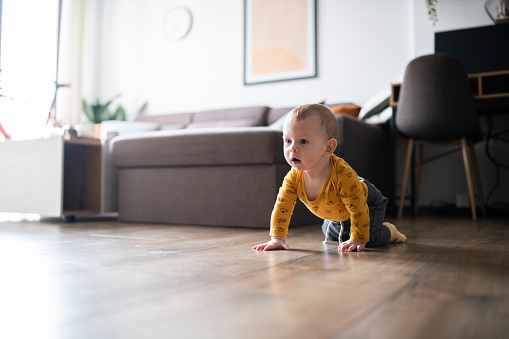 Baby boy crawling on the floor and smiling.