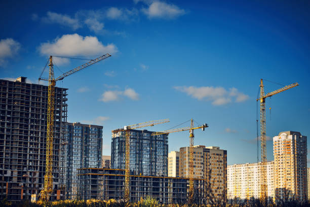 istock Group of tower cranes on the construction site against blue sky. Cranes for construction of high-rise buildings. Real estate construction. Concept of urban development and architecture. 1472405539