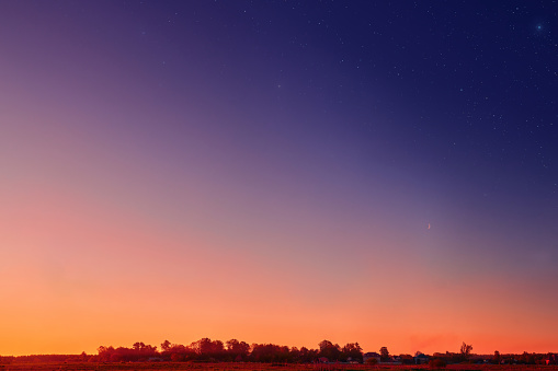 Sunset on the clear sky. Color gradient of the morning sky. Dusk sky with stars above horizon. Beautiful bright sunrise on the sky, background.