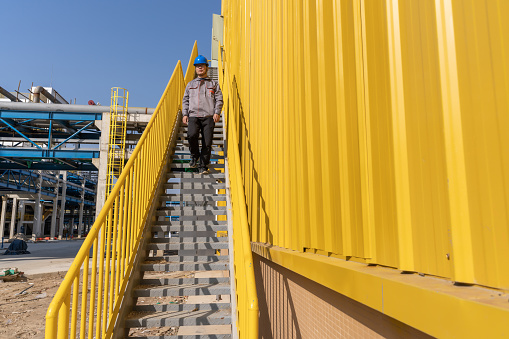 A male worker climbed the stairs next to the yellow factory building
